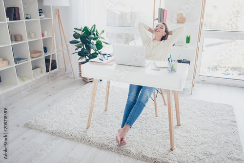 Full size portrait of lovely woman sitting at desk holding hands behind the head keeping eyes closed having laptop computer on the table dreaming about vacation weekend