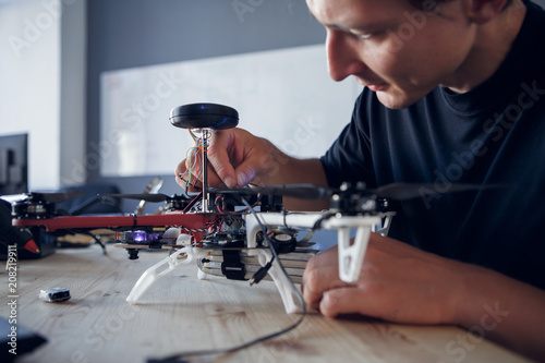 Image of engineer fixing square copter at table