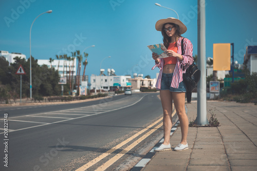 Where is that place. Full length portrait of concentrated girl reading the map while standing near the road in tropical place