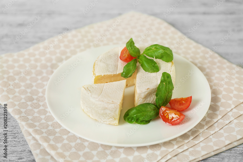 Delicious brie cheese with basil and cherry tomatoes on plate