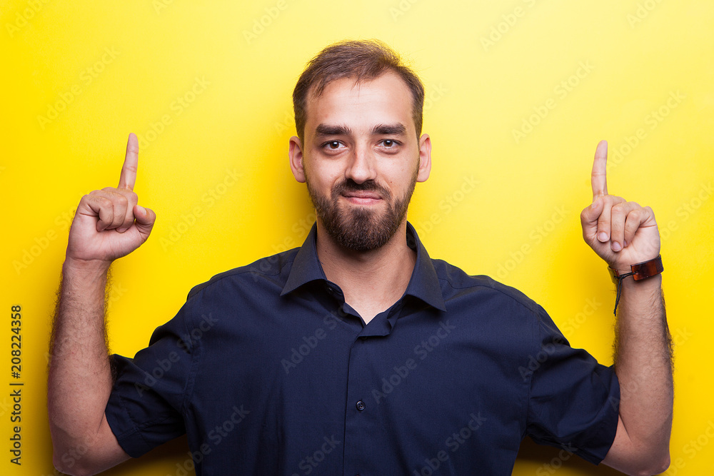 great looking young man pointing up on yellow background