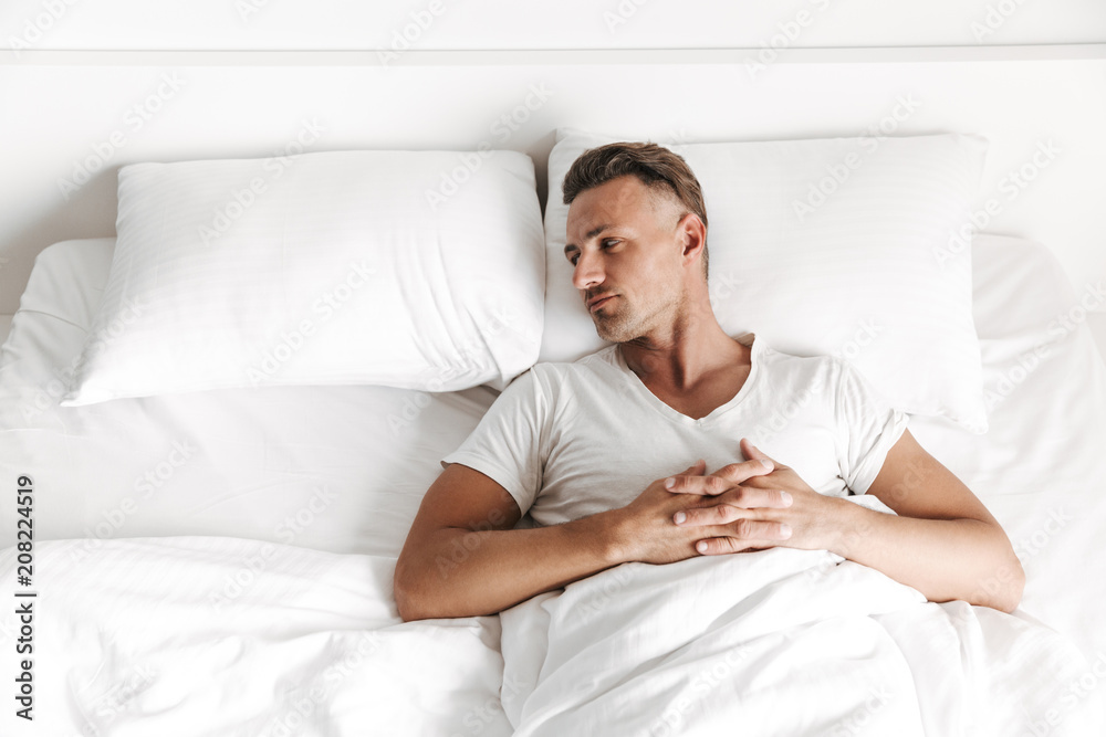 Upset man laying in bed and looking away Upset man laying in bed and looking away