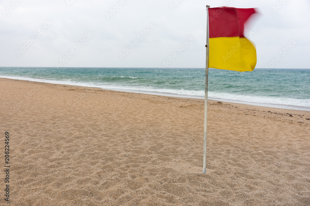 Red and yellow warning flag flying in the wind Red and yellow warning flag flying in the wind