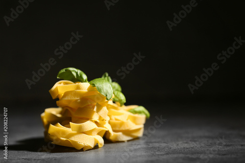 Uncooked fettuccine pasta on table against dark background