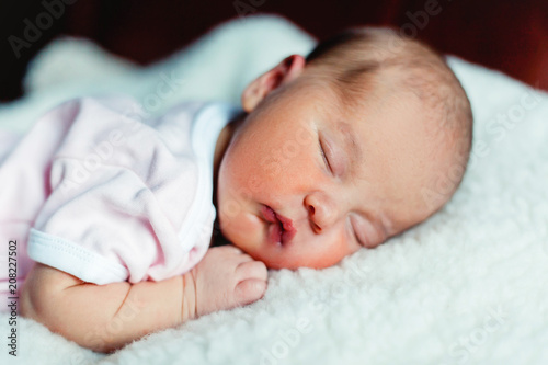 Soft portrait of peaceful sweet newborn infant baby lying on bed while sleeping in a bright room. Maternity family childhood innocence care concept