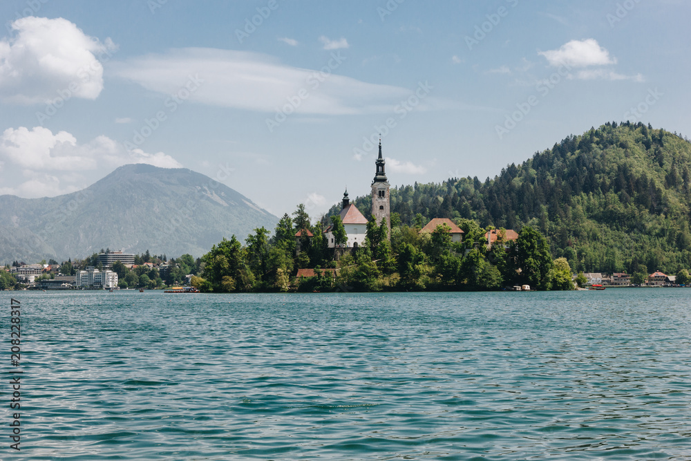 old architecture and green trees at bank on scenic mountain lake, bled, slovenia