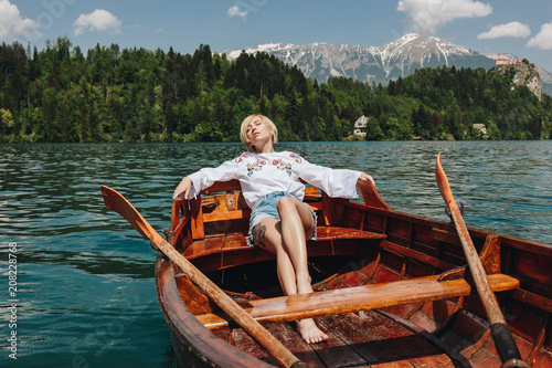 Photo beautiful young woman resting in boat at tranquil mountain lake, bled, slovenia