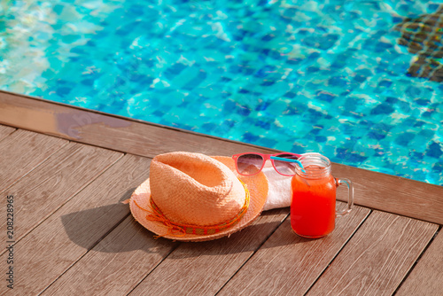 Water-melon fresh fruit smoothie drink with sunglasses and straw hat on swimming pool border - holiday concept