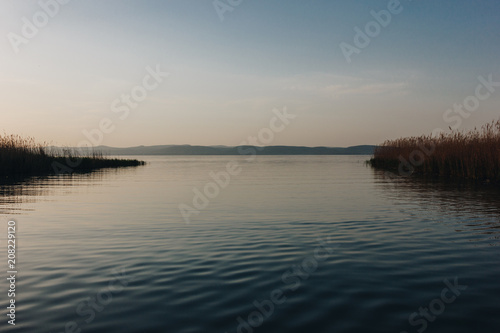 beautiful landscape with calm lake and hills in background at sunset, bled, slovenia