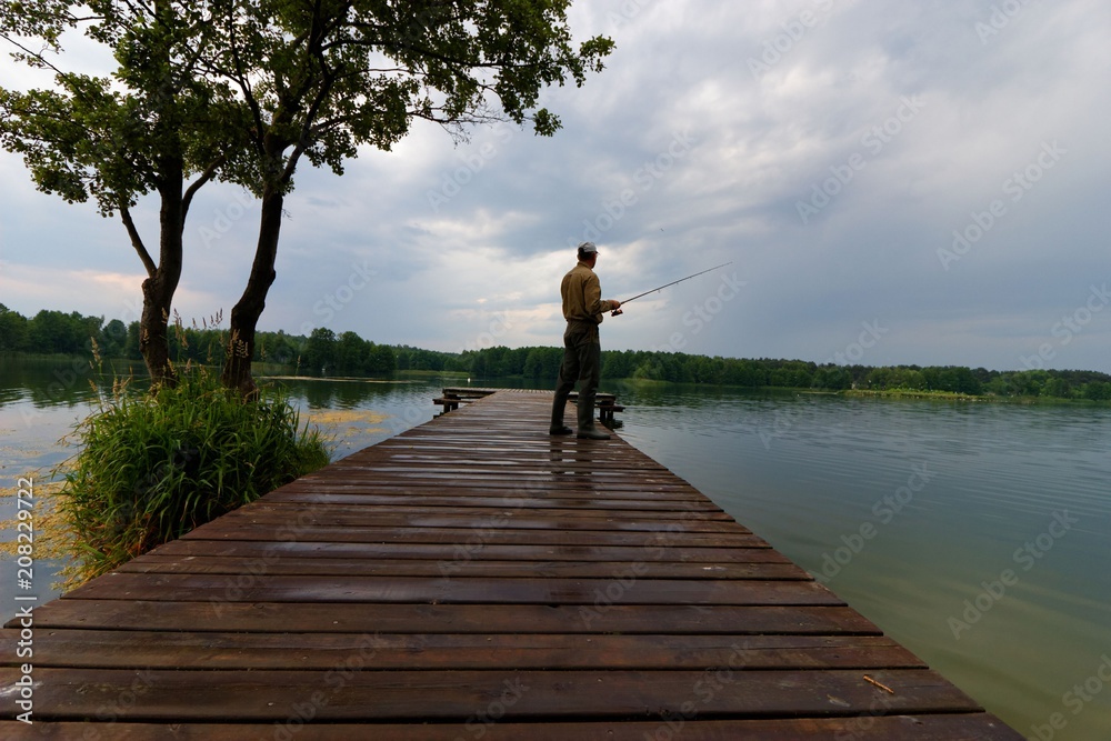 Fisherman catching the fish from wooden pier during cloudy day