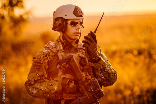 portrait of young soldier face with camouflage against a sunset background