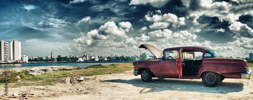 panoramic view of havana and malecon with old american car parked whit engine ploblem
