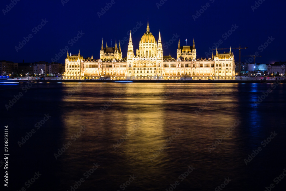 Illuminated Budapest parliament building at night with dark sky and reflection in Danube river