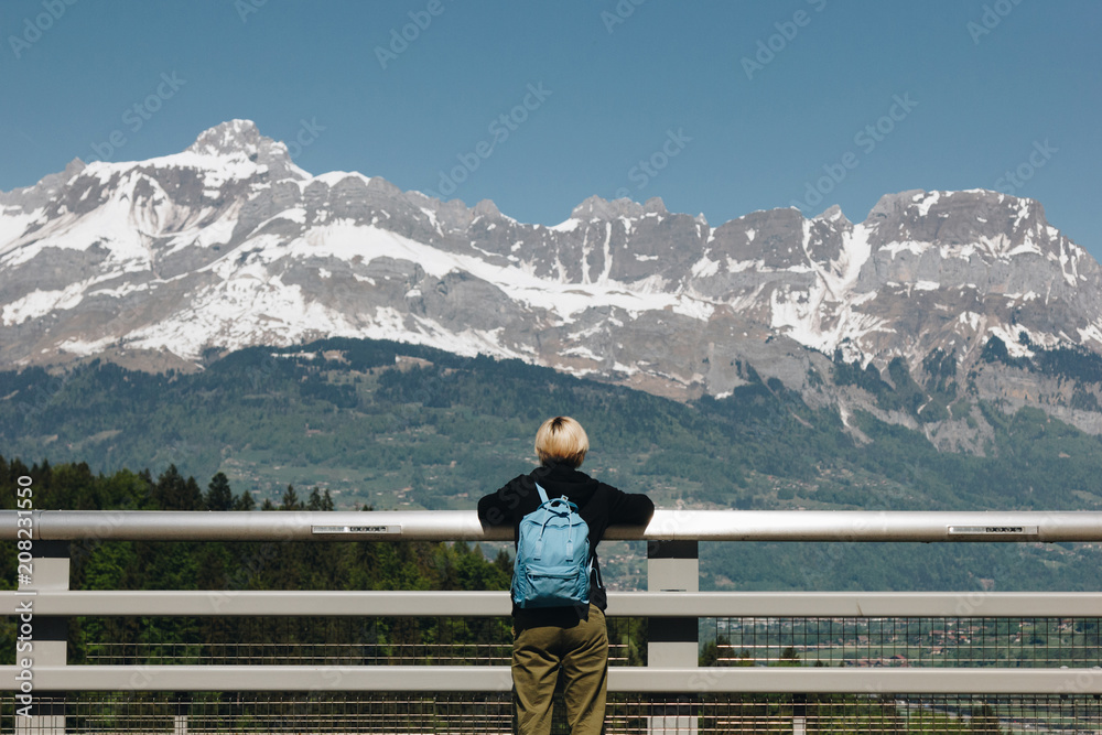 rear view of young woman with backpack looking at majestic snow-capped mountains, mont blanc, alps
