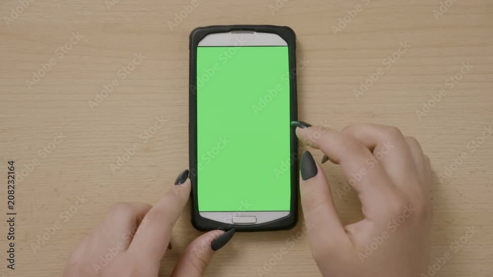 Top view of young businesswoman using smartphone making scrolling and sliding gestures on green touchscreen Top view of young businesswoman using smartphone making scrolling and sliding gestures on green touchscreen