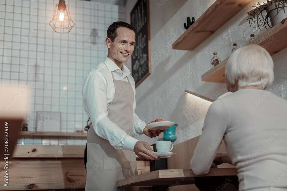 Cozy atmosphere. Handsome waiter expressing positivity while serving food Cozy atmosphere. Handsome waiter expressing positivity while serving food