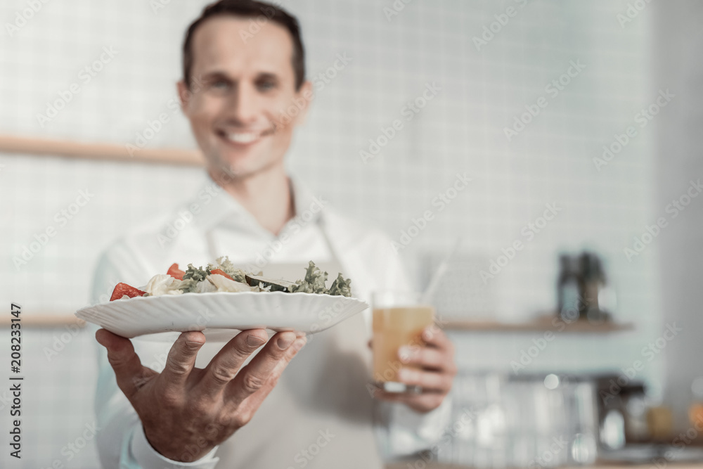 Refresh yourself. Pleased waiter smiling while serving dish to his client Refresh yourself. Pleased waiter smiling while serving dish to his client