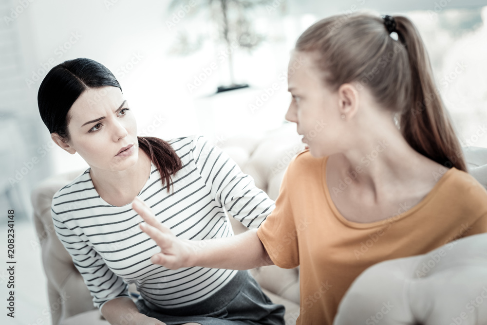 Stop talking. Unsatisfied teen girl stretching hand while concerned female psychologist looking at her and frowning Stop talking. Unsatisfied teen girl stretching hand while concerned female psychologist looking at her and frowning