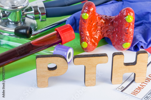 Medical laboratory abbreviation PTH or parathyroid hormone, which is secreted by  parathyroid gland and using his blood test may diagnose organ disease. Word PTH near model of thyroid, lab test tube photo
