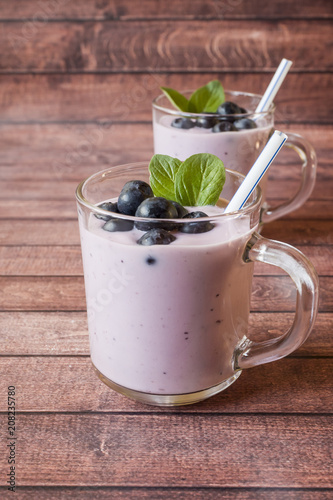 Blueberry yogurt in glass cups with fresh blueberries and mint on a wooden rustic table