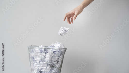 Woman hand throwing crumpled paper in basket photo