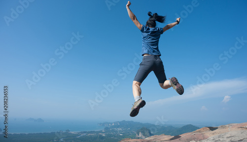 Woman jumping on mountain top cliff edge