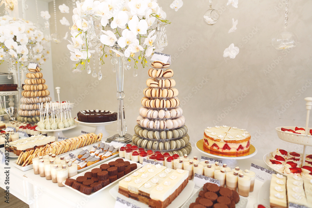 luxury wedding catering, table with modern desserts, cupcakes, sweets with fruits. delicious candy bar at expensive wedding reception.