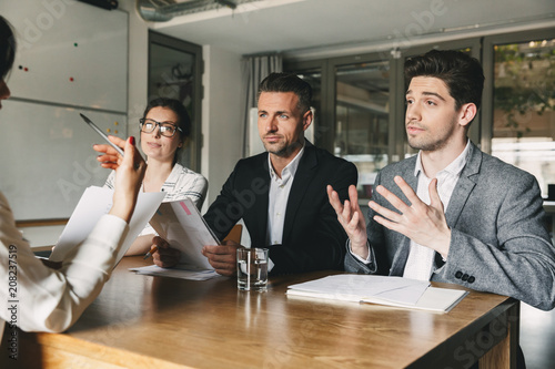 Business, career and placement concept - three executive directors or head managers sitting at table in office, and negotiating with new personnel during interview photo