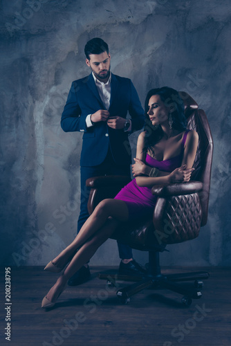Portrait of sexual hot woman in purple dress sitting in leather chair trendy man unbutton jacket looking at bitch having erection lovely attractive couple isolated on grey dark background