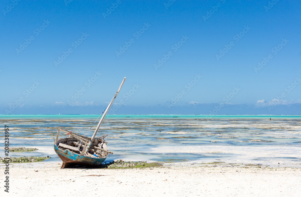 Tropical beach with old boat at low tide in Jambiani, Zanzibar, Tanzania Africa