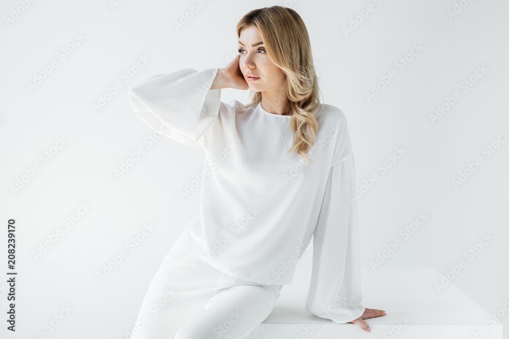 portrait of beautiful pensive woman in white clothing sitting on cube isolated on white portrait of beautiful pensive woman in white clothing sitting on cube isolated on white