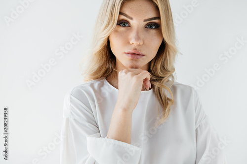 portrait of beautiful blond woman in white clothing posing on white backdrop