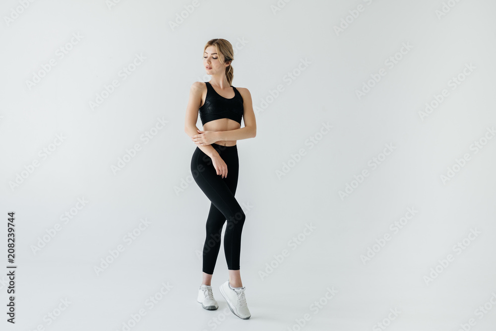 young blond sportswoman in black sportswear posing isolated on grey young blond sportswoman in black sportswear posing isolated on grey