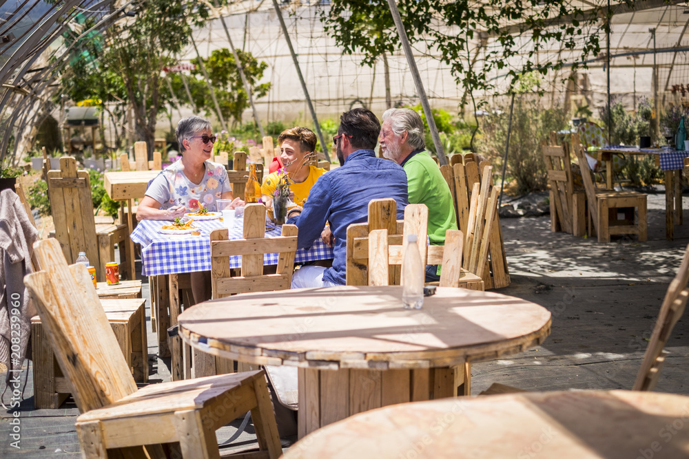 family at lunch together outdoor natural scenic place with a lot of recycled wood furnitures made with pallets. enjoy and smile leisure activity caucasian people in a sunny day of vacation weekend family at lunch together outdoor natural scenic place with a lot of recycled wood furnitures made with pallets. enjoy and smile leisure activity caucasian people in a sunny day of vacation weekend
