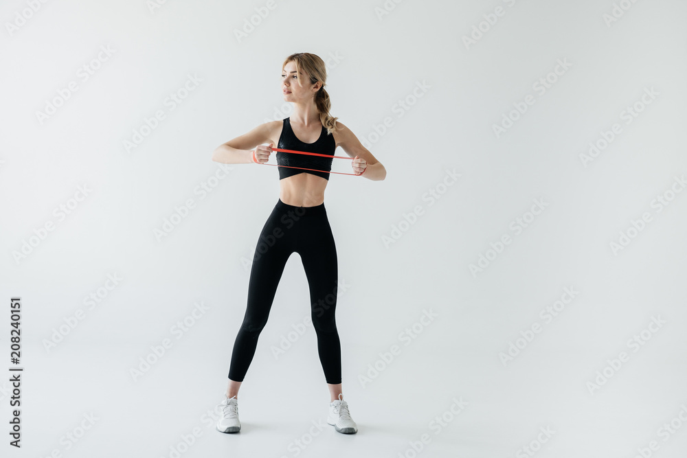 young athletic woman exercising with rubber tape isolated on grey young athletic woman exercising with rubber tape isolated on grey