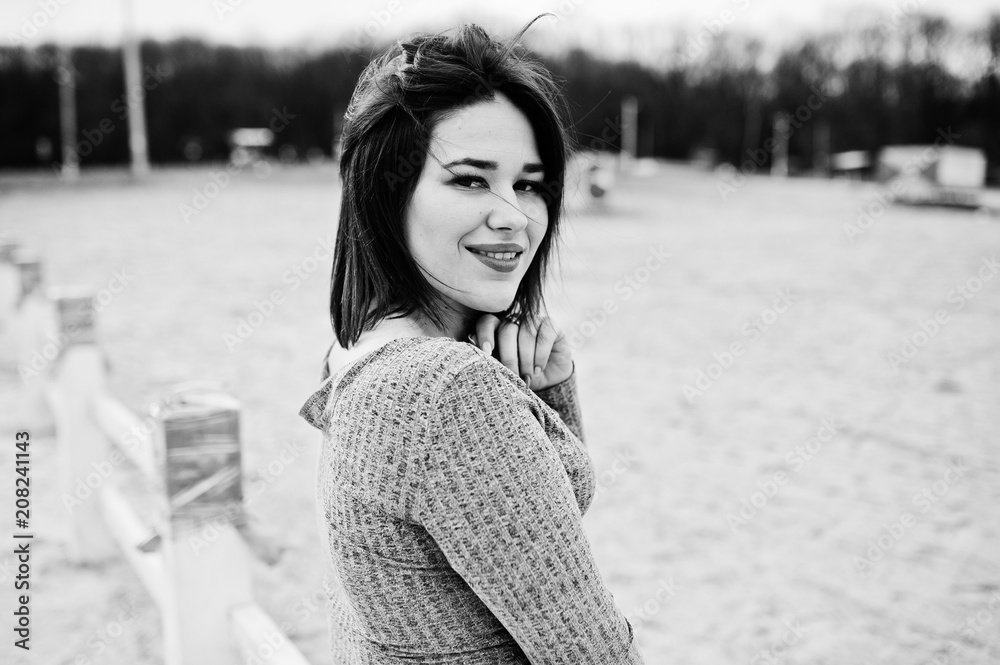 Portrait of brunette girl in gray dress sitting at white wooden construction. Portrait of brunette girl in gray dress sitting at white wooden construction.