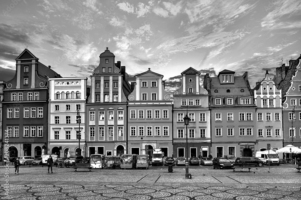 Central market square in Wroclaw Poland with old houses, street lamp and walking tourists people at gorgeous stunning evening sunset sunshine. Travel vacation concept. Black and white