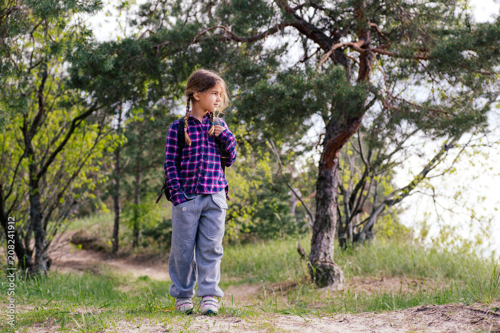 Little girl with backpack traveling in the forest Little girl with backpack traveling in the forest