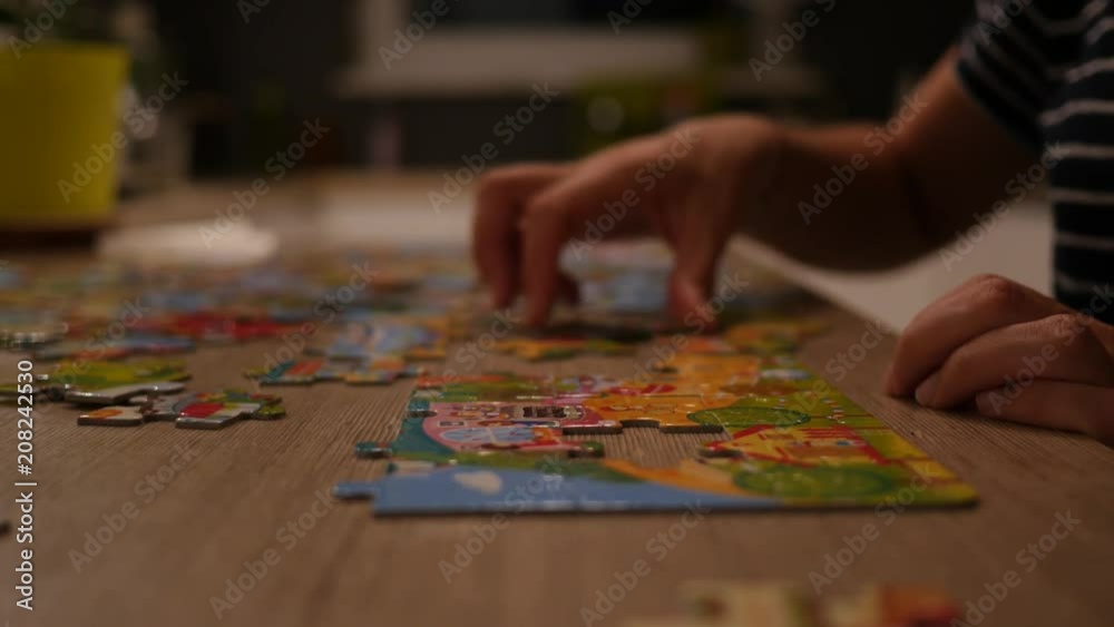 Single woman at home play folds puzzle at the kitchen table not to be bored Single woman at home play folds puzzle at the kitchen table not to be bored