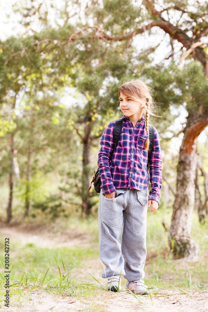 Little girl with backpack traveling in the forest Little girl with backpack traveling in the forest