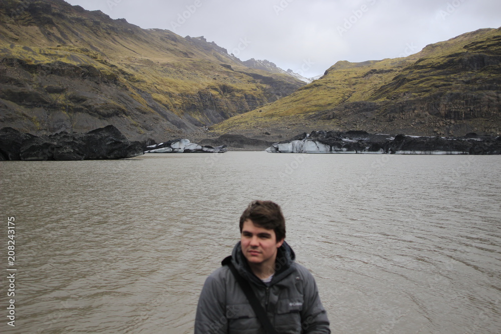 Fototapeta premium Young male tourist posing in front of mountains and icebergs in the background, photo taken in Iceland