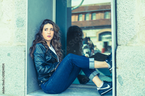 woman sitting on the window wearing leather jacket