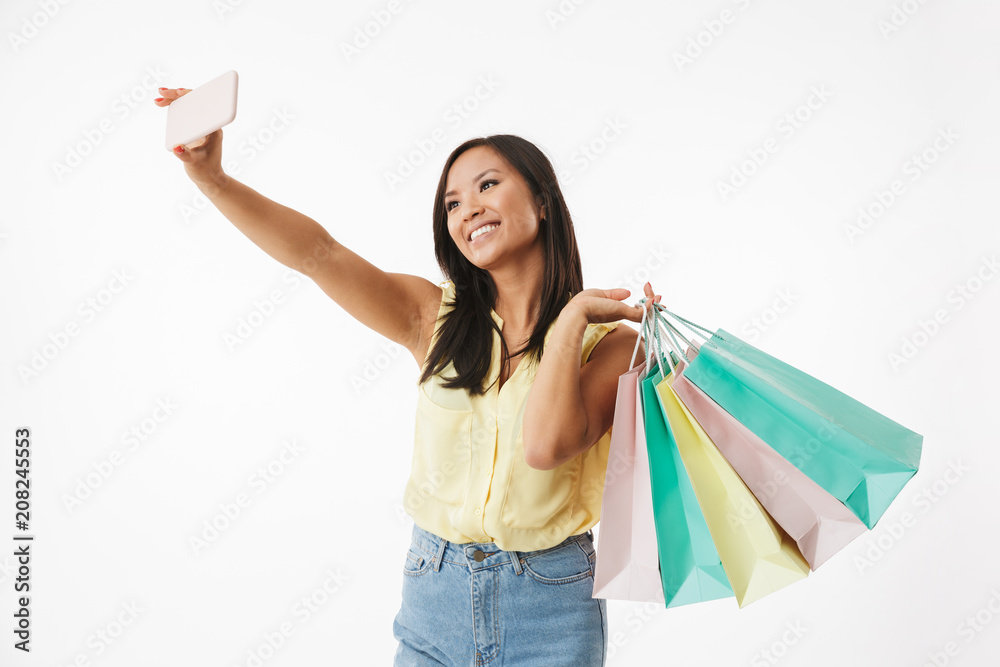 Happy emotional young asian woman with shopping bags make selfie by mobile phone. Happy emotional young asian woman with shopping bags make selfie by mobile phone.