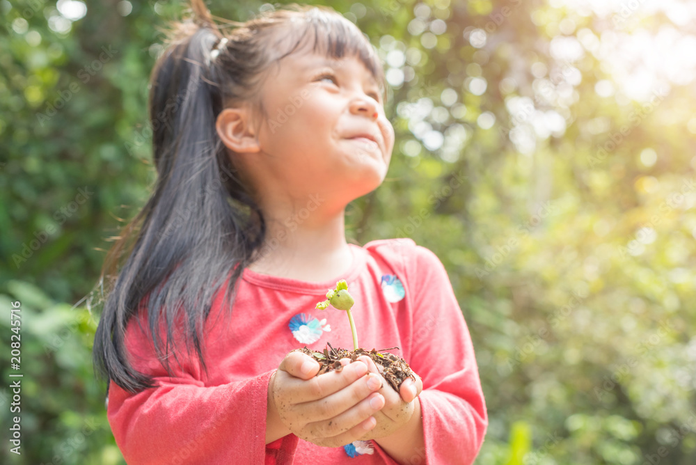 Kid holding young plant in hands against spring green background. Ecology concept Kid holding young plant in hands against spring green background. Ecology concept