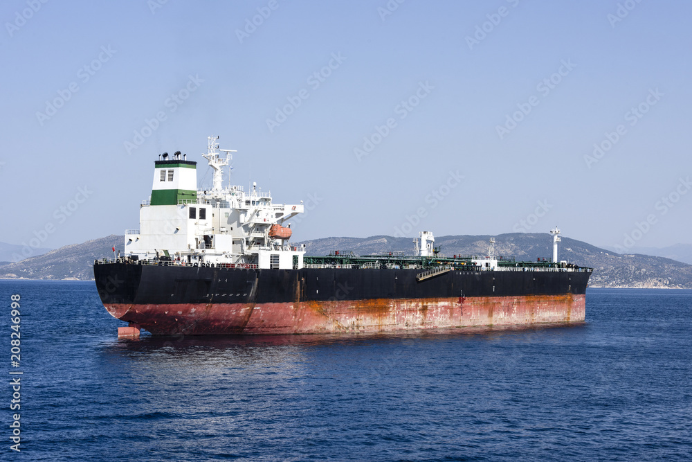 Greece, near Piraeus: Big tanker Golden Energy on blue ocean water with skyline of mountain chain in the background - concept transport boat ship sea travel oil business energy supply.