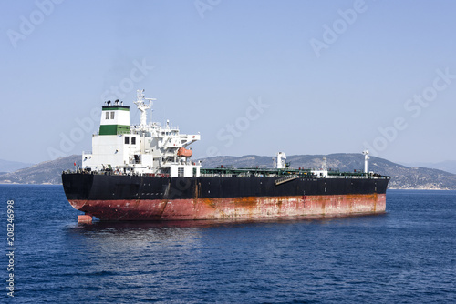 Greece  near Piraeus  Big tanker Golden Energy on blue ocean water with skyline of mountain chain in the background - concept transport boat ship sea travel oil business energy supply.