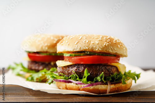 Classical burger with grilled meat, tomatoes, cheese, onion, cucumber and lettuce served on wooden table