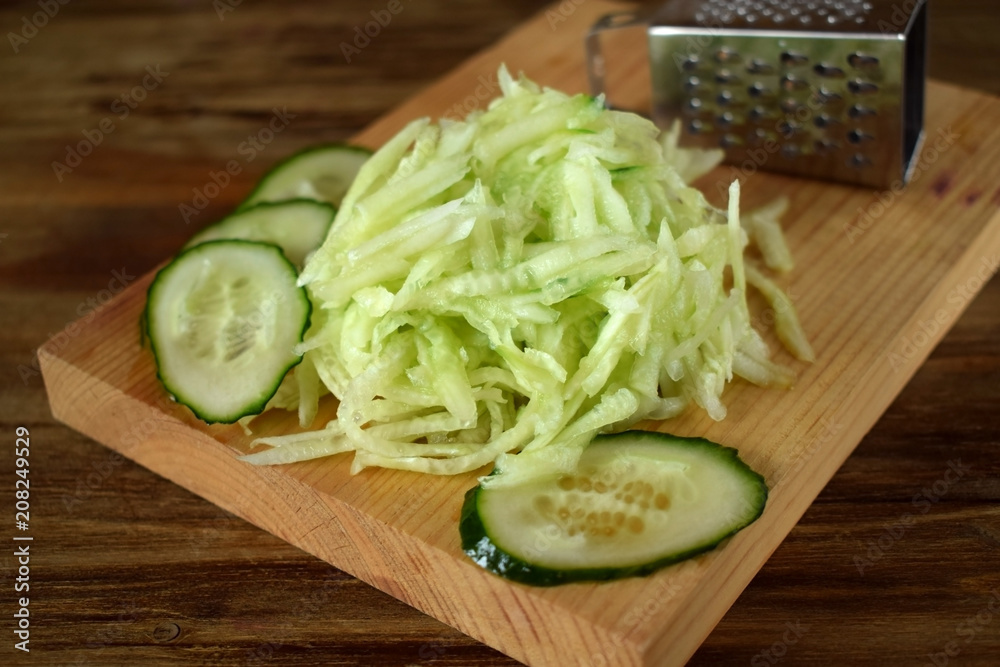 Grated cucumber on a wooden board. Ingredient for a meal Grated cucumber on a wooden board. Ingredient for a meal
