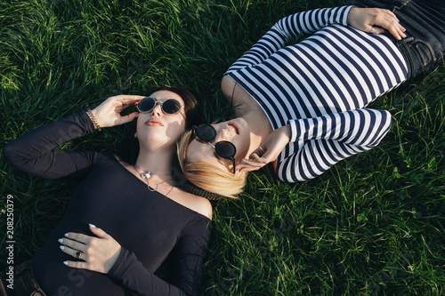 high angle view of young women in stylish clothes lying on green grass in park photo