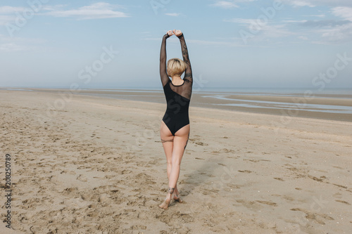 rear view of attractive young woman in black bodysuit on sandy beach photo